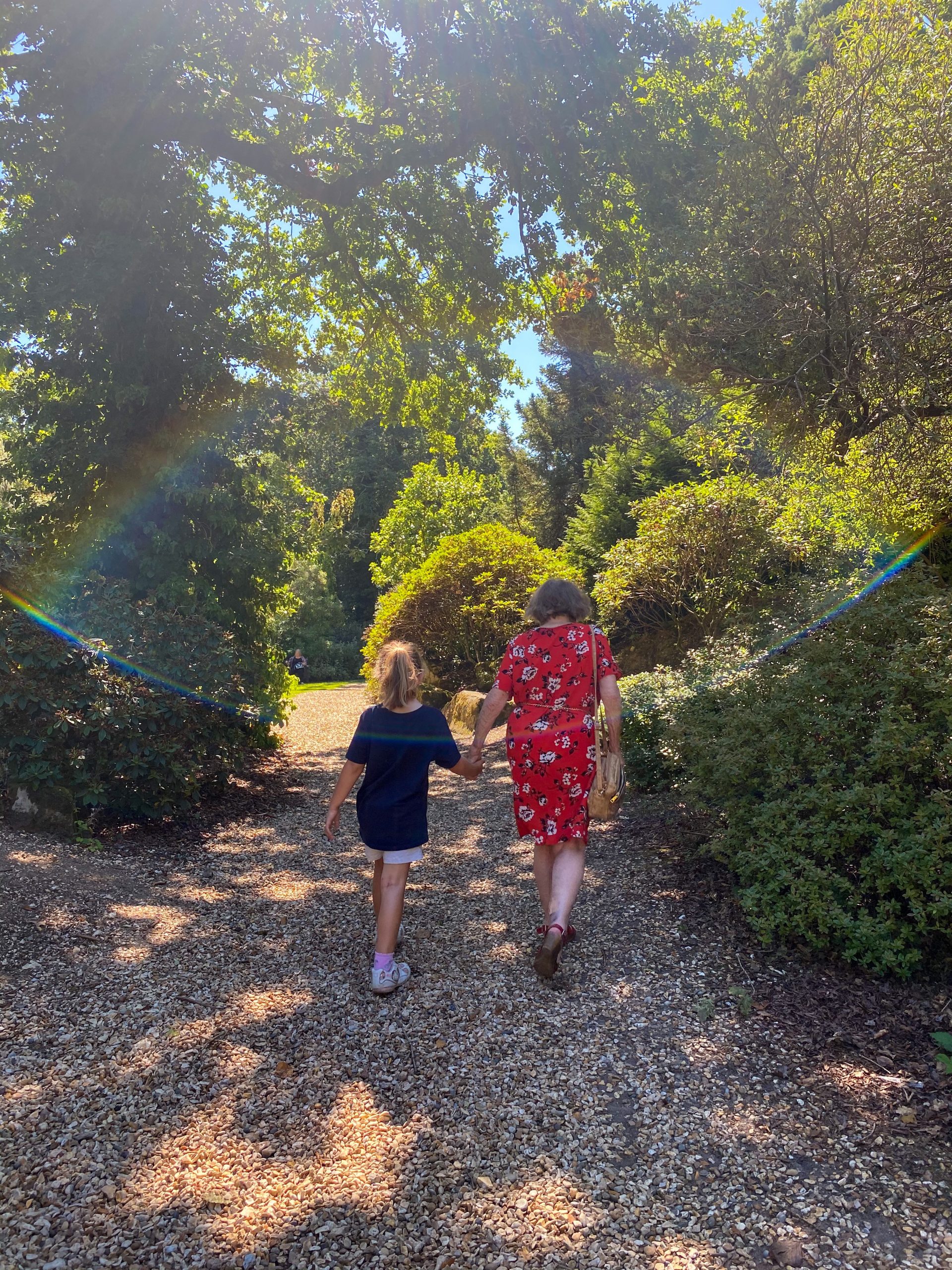woman and child walking through gardens with rainbow lighting 