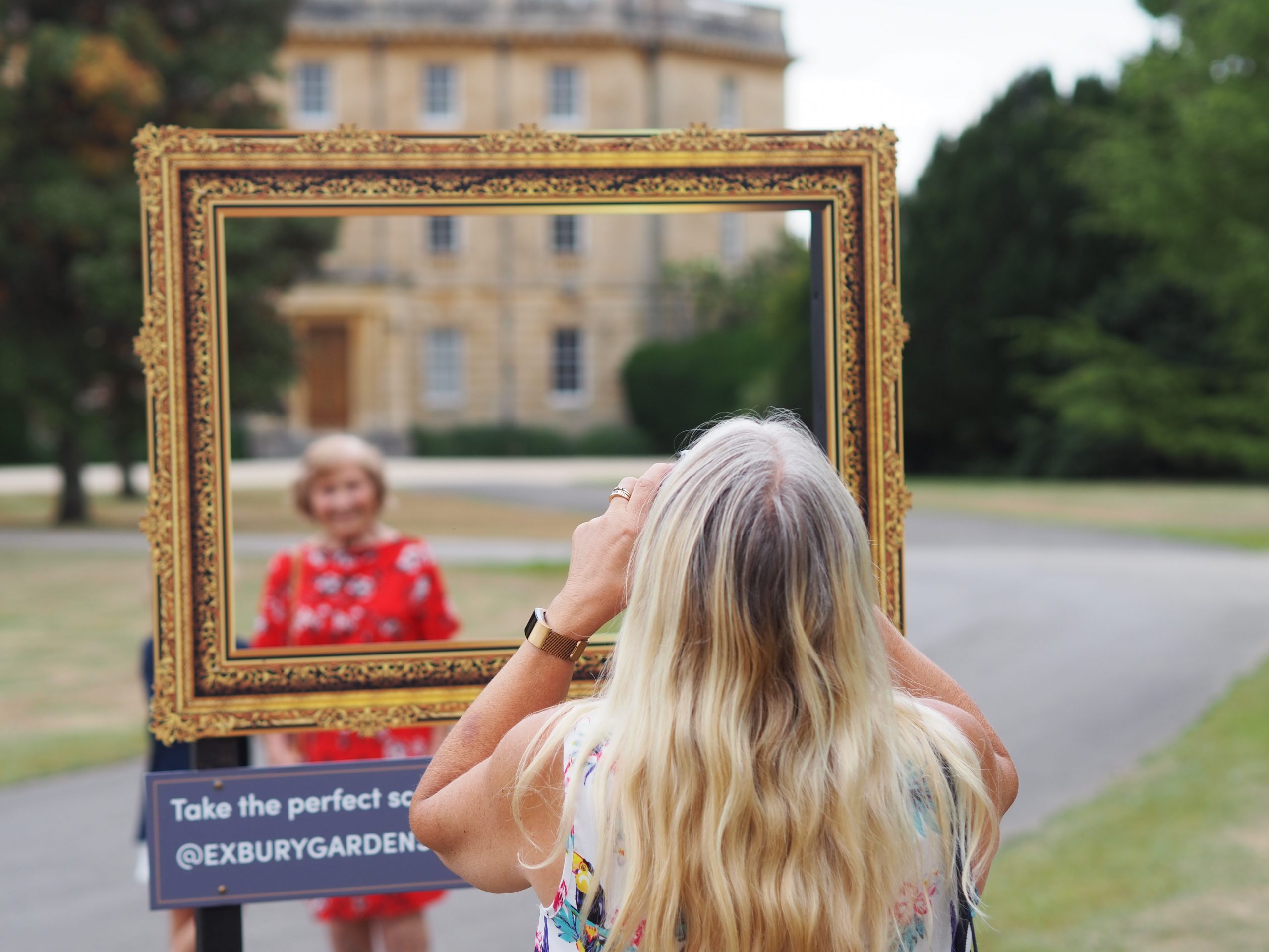 woman taking photo of woman and child using photo prop frame